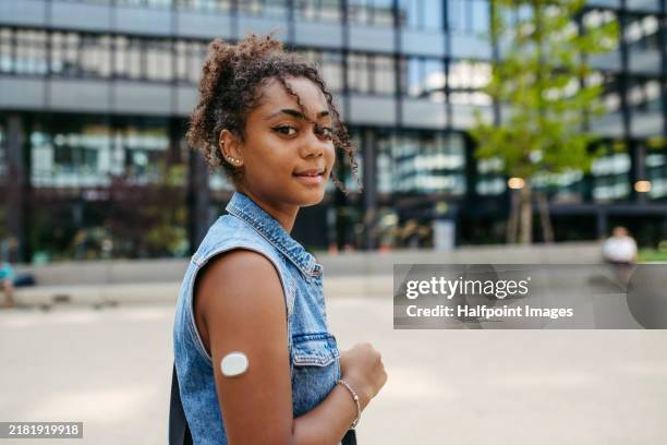 arm with cgm sensor on it. young diabetic woman in the city, walking on street, looking at camera. - hormone therapy stock pictures, royalty-free photos & images