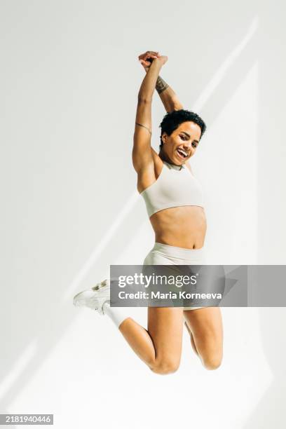 portrait of a jumping female athlete against the white background. - thin stock pictures, royalty-free photos & images