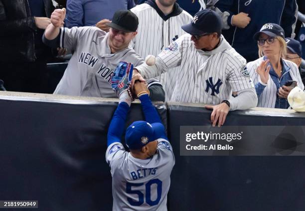 Fans Austin Capobianco and John Peter interfere with Mookie Betts of the Los Angeles Dodgers as he attempts to catch a fly ball in foul territory...