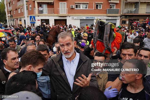 King Felipe VI of Spain speaks with some residents as others heckle him during his visit to Paiporta, in the region of Valencia, eastern Spain, on...