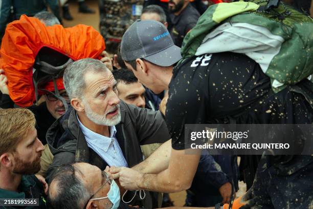 King Felipe VI of Spain talks with a person as angry residents heckle him during his visit to Paiporta, in the region of Valencia, eastern Spain, on...