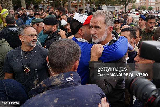 King Felipe VI of Spain is hugged by a man as other angry residents heckled him during his visit to Paiporta, in the region of Valencia, eastern...