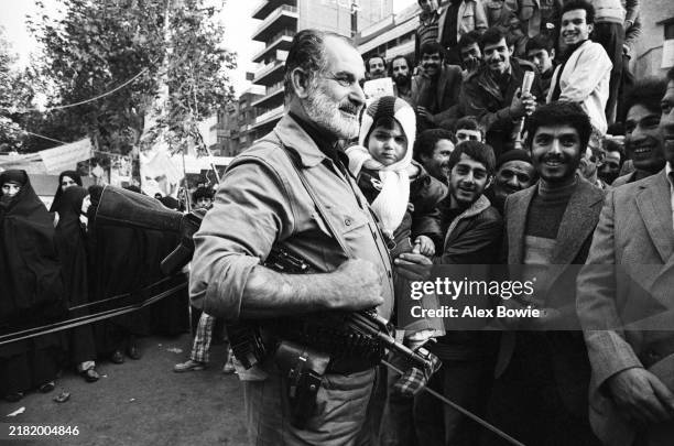 An Islamic Revolutionary Guard holding a child receives a friendly welcome from a group of men gathered in front of the occupied US Embassy in...