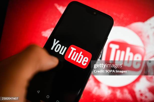In this photo illustration, a Youtube logo is displayed on a smartphone with Youtube logo in the background.