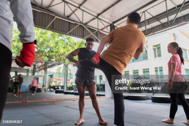 asian kickboxing instructor teaching students method of kicking at gym stock photo - self defence stock pictures, royalty-free photos & images