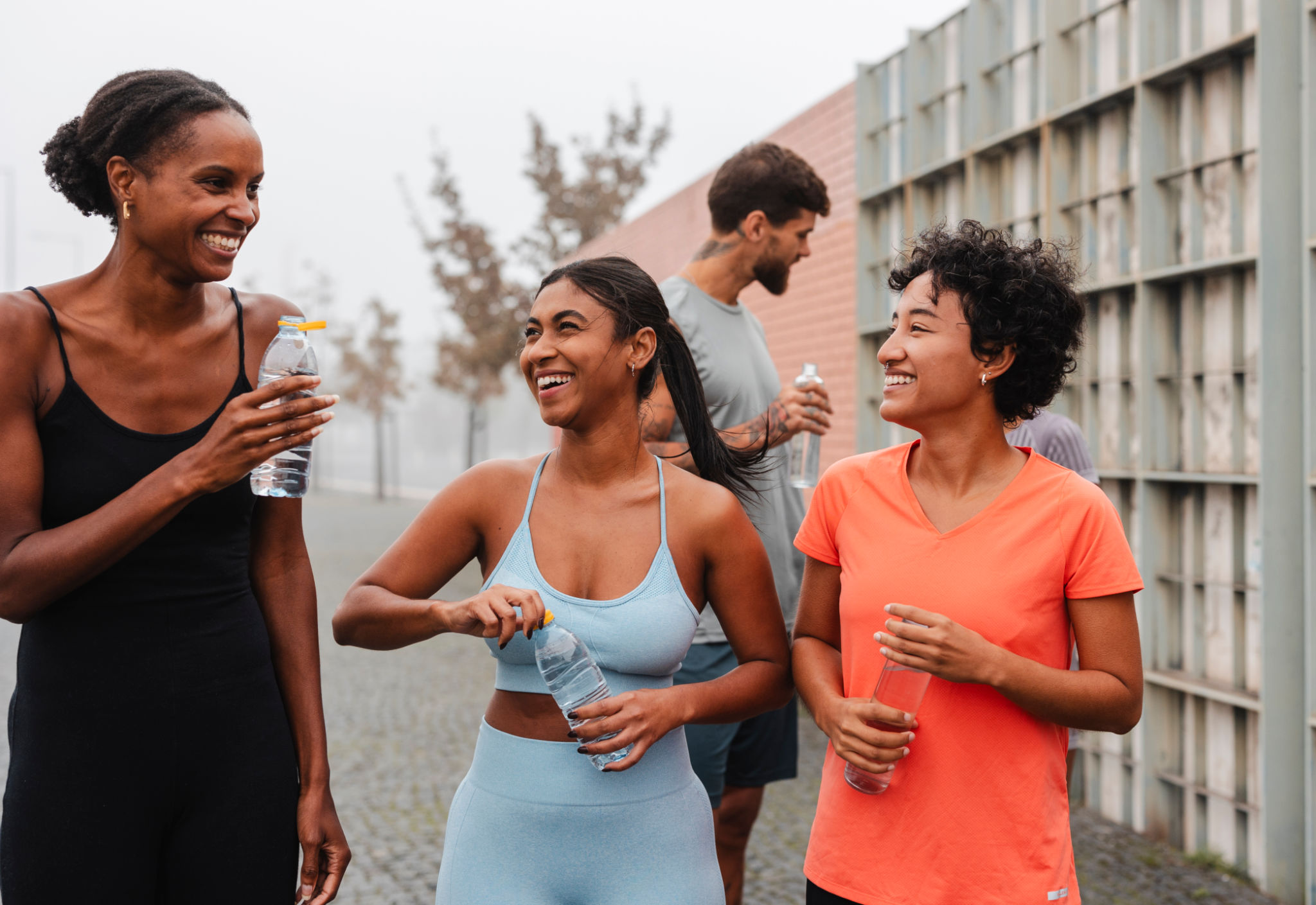 Group of happy athletes hydrating after training in the city Group of happy athletes hydrating after training in the city
