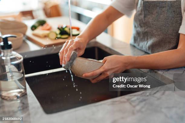 closeup of female hand washing dishes in kitchen sink - serviesgoed stockfoto's en -beelden
