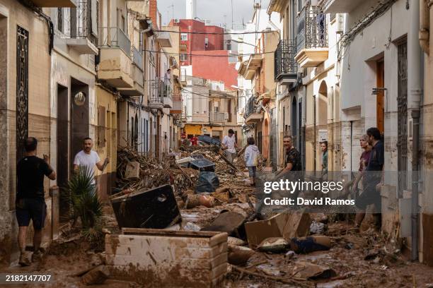 Residents clean up a mud-and-debris-covered street after flooding hit large parts of the country on October 31, 2024 in the Paiporta municipality of...