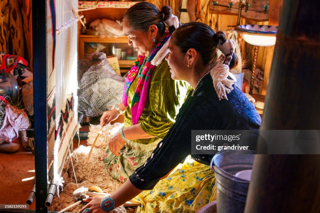 Traditional Elderly Navajo Woman Working to Make an Authentic Blanket on a Loom, Teaching Her Granddaughter and Spending Quality Time in a Traditional Navajo Hogan in Monument Valley Southern Utah, Northern Arizona