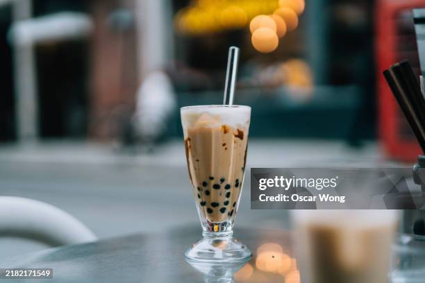 a glass of boba milk tea, taiwanese bubble tea, on the table at pavement cafe - bubble tea stock pictures, royalty-free photos & images