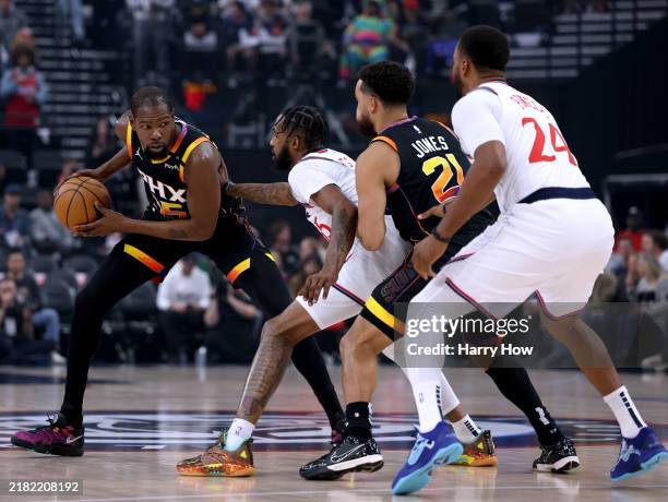 Kevin Durant of the Phoenix Suns holds the ball in front of Derrick Jones Jr. #55 and Norman Powell of the LA Clippers with Tyus Jones during the...