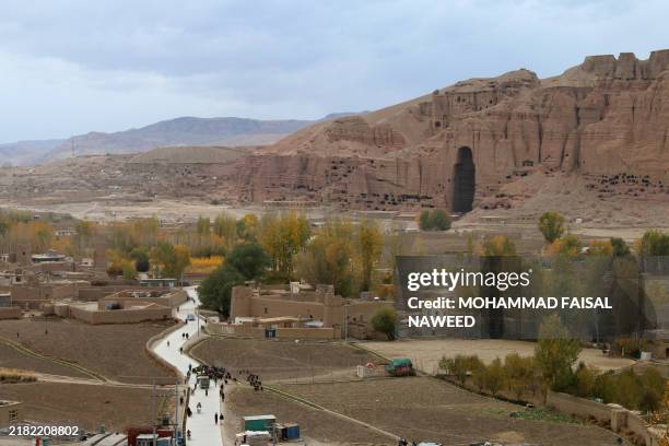 Afghan men walk on a road leading to the site where the Buddha statue once stood before being destroyed by the Taliban in March 2001, in Bamiyan...