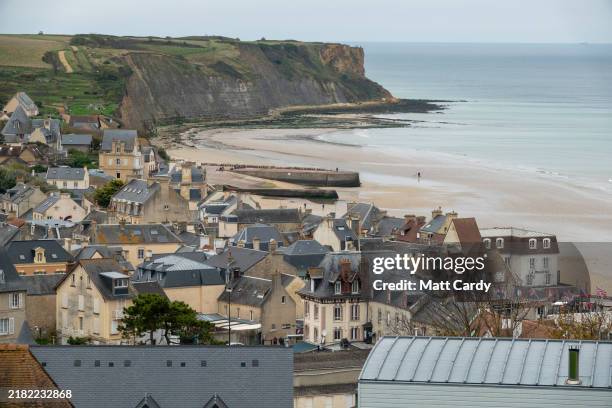 People walk around the remains of the Mulberry B harbour at low tide at Gold Beach on October 30, 2024 in Arromanches-les-Bains, France. This year...