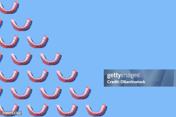 lower denture pattern, on the left side, on blue background. dentist, implants, dental, clinic and treatment. - dentures stock pictures, royalty-free photos & images