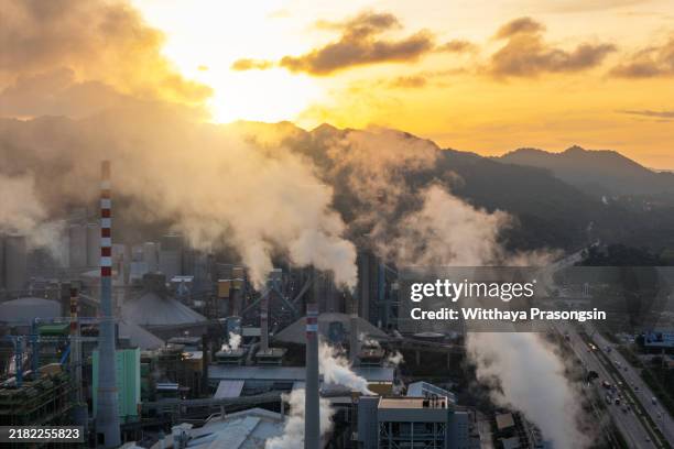 industrial factory emitting smoke during golden sunset - pegada ecológica imagens e fotografias de stock
