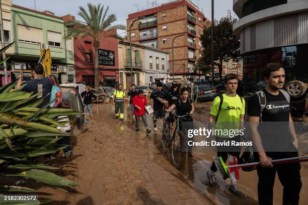 Volunteers walk through muddy waters in a street on November 1, 2024 in the Alfafar municipalities of Valencia, Spain. By Friday morning, Spanish...