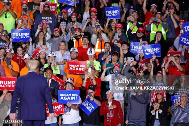 Former US President and Republican presidential candidate Donald Trump looks at supporters as he walks on stage during a campaign rally at Van Andel...