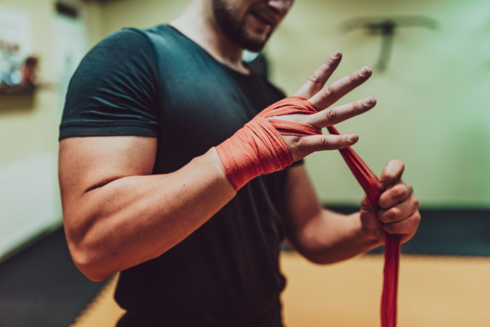 A male hand of boxer or fighter with red boxing bandages before the fight or training in sport gym. A male hand of boxer or fighter with red boxing bandages before the fight or training in sport gym.