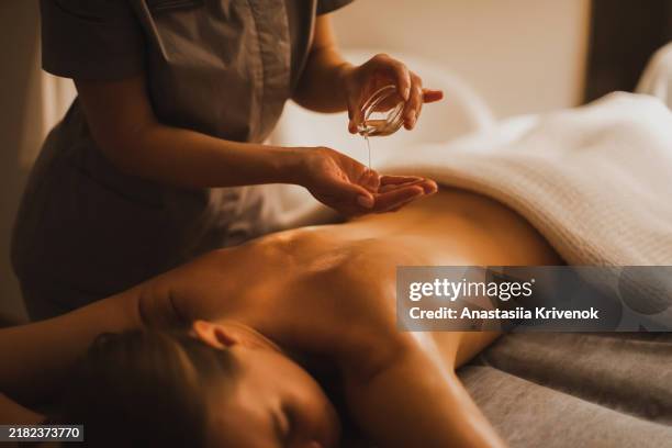 young european woman enjoying relaxation atmosphere during full body massage at spa, room decorated with candles and soft light. - spa treatment stock pictures, royalty-free photos & images