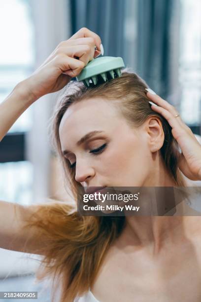 relaxation and self-care: woman using scalp massager at home - cuero cabelludo fotografías e imágenes de stock