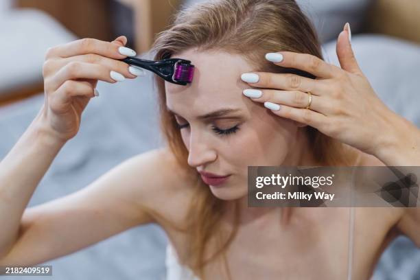 woman using dermaroller for skincare routine at home. - receding hairline stock pictures, royalty-free photos & images