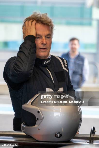 Fabien Roussel national secretary of the Communist Party in a racing suit with his helmet placed in front of him on the spoiler of a racing car runs...