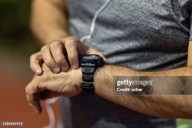 inconnu homme mature faisant de l’exercice à l’extérieur vérifiant son pouls sur sa montre intelligente - montre bracelet photos et images de collection