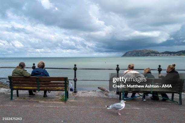 Members of the public sit on benches and look at the view on September 25, 2024 in Llandudno, Wales.