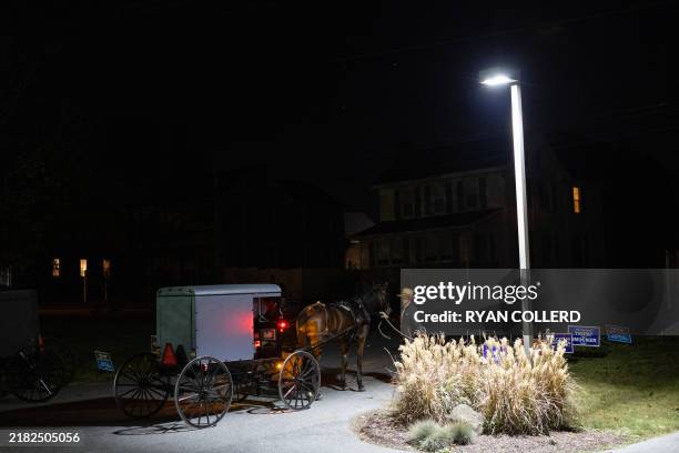 An Amish man stands next to a horse and buggy outside a polling location in the Leacock Township Municipal building in Intercourse, Pennsylvania, on...
