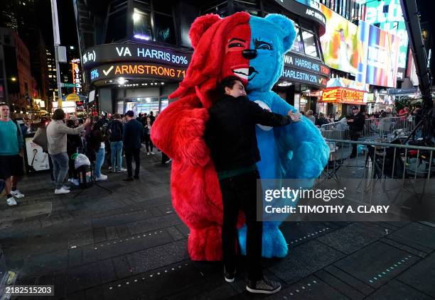 Person dressed as a unity bear, with the colors of the Democratic and Republican party, gives people hugs as the election results are displayed on...