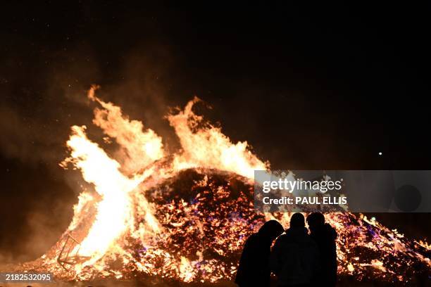 People stand around a large bonfire in Birkenhead near Liverpool, northwest England, on November 5, 2024. People around Britain light bonfires and...