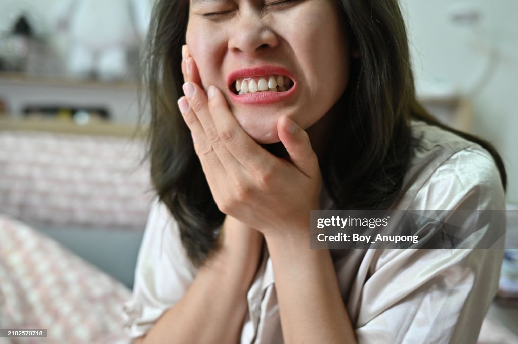 Cropped shot view of Asian woman having toothache problem. A toothache refers to pain in or around your tooth.