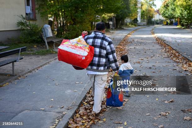 Man with child walks at the site of the former emergency reception camp for refugees and resettlers from the GDR, today temporary home for refugees...