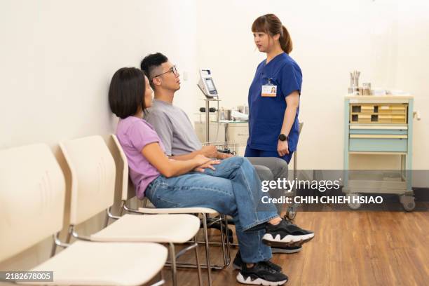 an asian female healthcare worker is triaging a male patient in the emergency room and analyzing his condition. - triage stock pictures, royalty-free photos & images