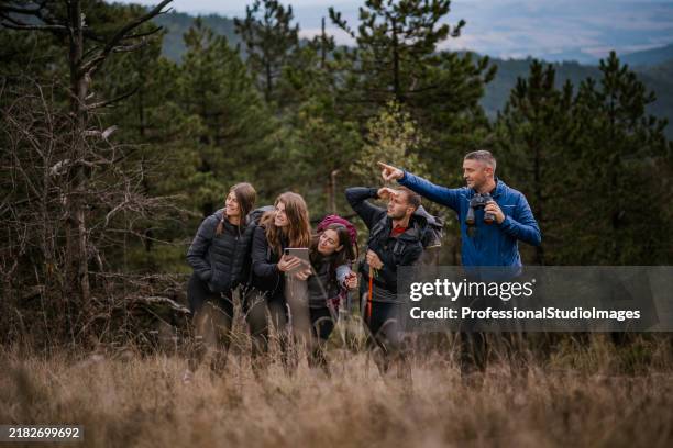 gruppe von outdoor-entdeckern, die während ihres wanderabenteuers ein tablet zur navigation in einem üppigen wald verwenden - fünf personen stock-fotos und bilder