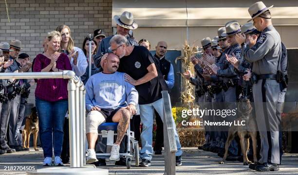 New York State trooper Thomas Mascia gets a kiss from his father, Thomas, as he leaves in a wheelchair from Nassau University Medical Center in East...