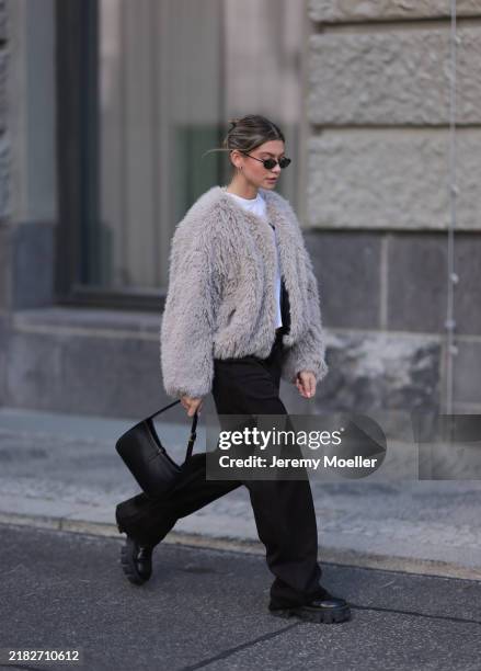 Sophia Geiss is seen wearing oval rimless black sunglasses from Vehla Eyewear, two different-sized gold hoop earrings and a gold stud earring, a...