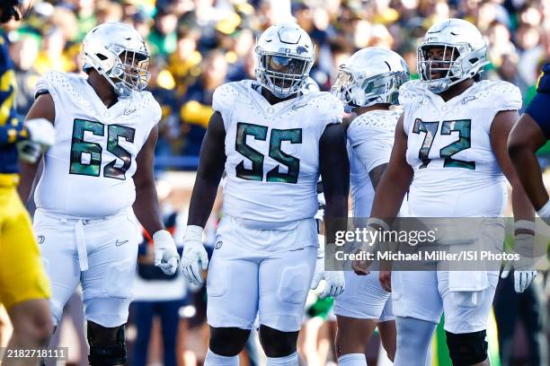 Ajani Cornelius, Marcus Harper II, Iapani Laloulu listen to the play call from Dillon Gabriel of the Oregon Ducks during a game between University of...