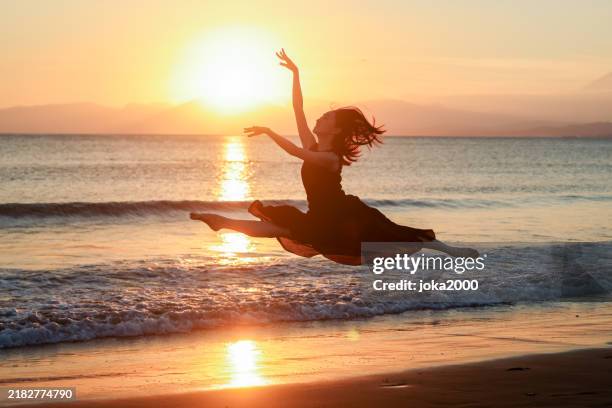 beautiful young lady jumping in sunset beach - dancer stock pictures, royalty-free photos & images