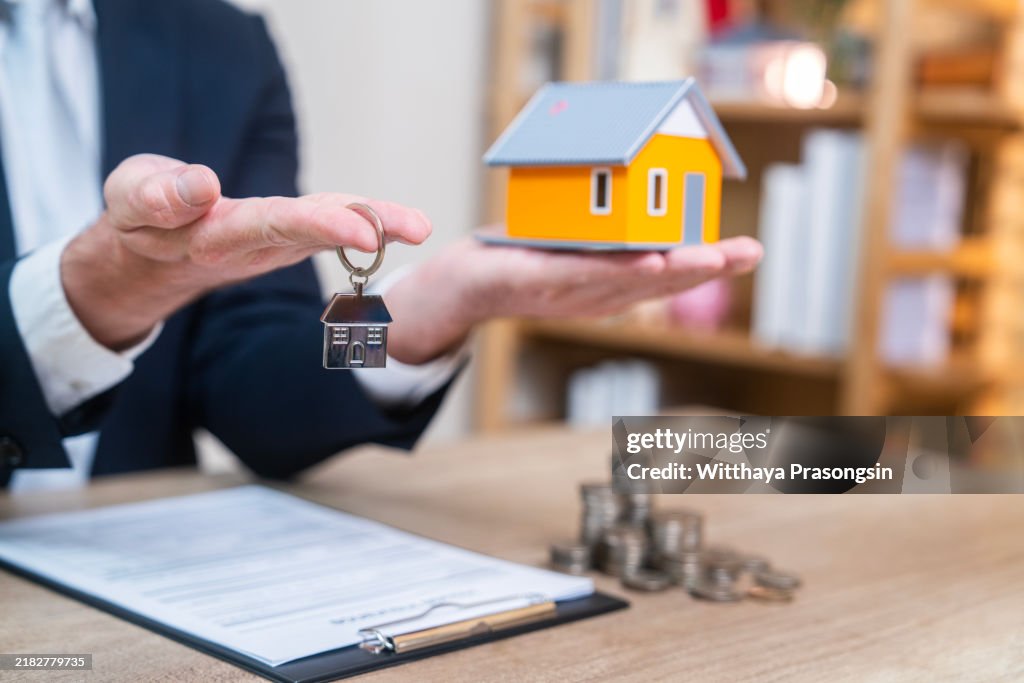 Real Estate Agent Holding Keys and Small House Model