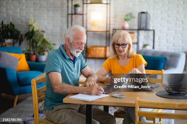 pareja de la tercera edad usando computadora portátil mientras planifica su presupuesto de la casa - costo de vida fotografías e imágenes de stock