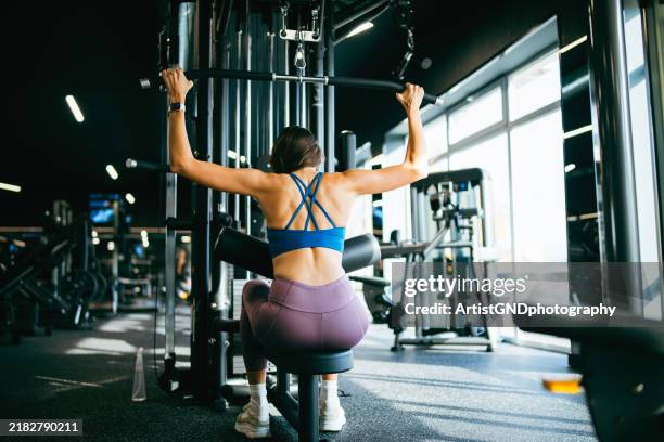 woman exercise with lat pulldown machine in gym. - fitnessapparaat stockfoto's en -beelden