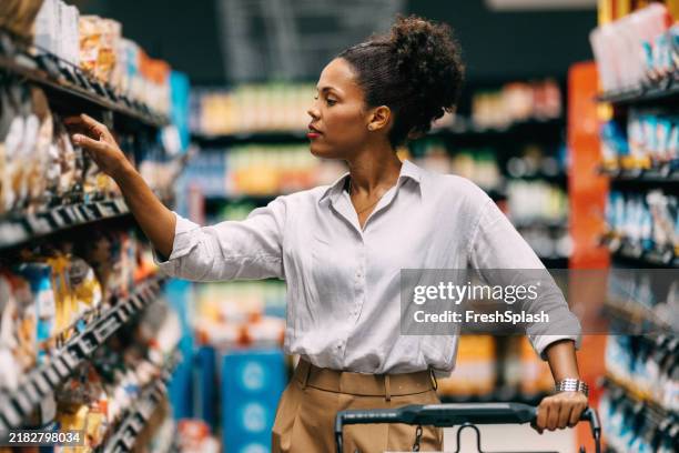 femme faisant ses courses dans l’allée du supermarché à la recherche de produits - libre service photos et images de collection