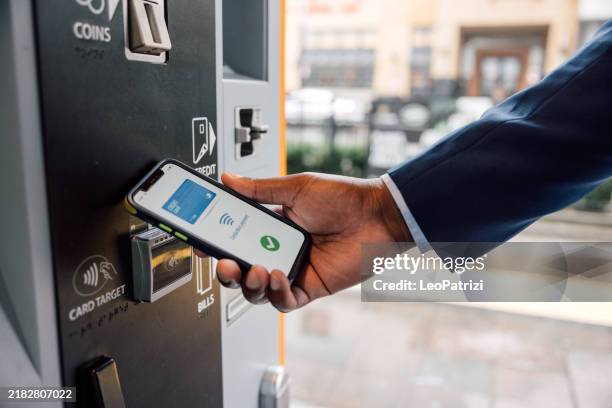 businessman buying a ride ticket from vending machine using contactless mobile payment - work vending machine stock pictures, royalty-free photos & images