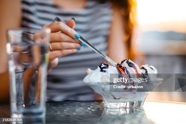 young woman eating banana split by the riverside café - gefrorene süßspeise stock-fotos und bilder