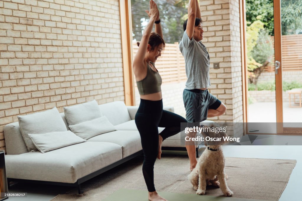 Young Asian couple working out together with their dog at home