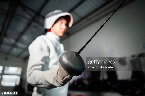 close-up of a man holding sword at a health club - fencing sport stock pictures, royalty-free photos & images