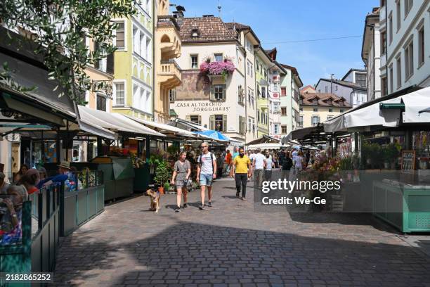 tourists and locals stroll through the weekly market in the streets of bolzano's old town. - bolzano stock pictures, royalty-free photos & images