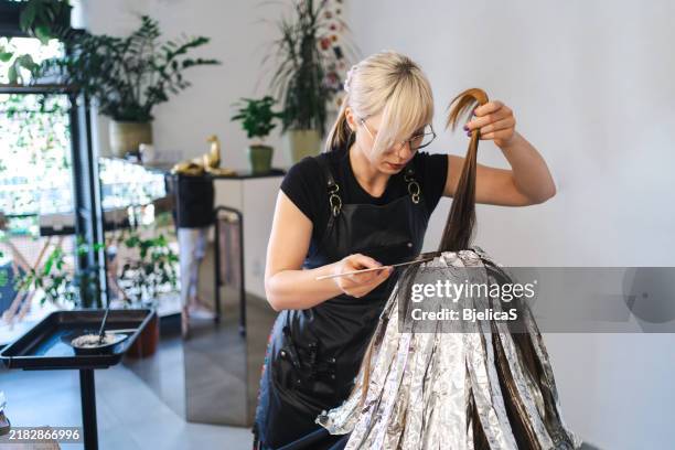 parrucchiere che colora i capelli di un cliente in salone - tintura per capelli foto e immagini stock