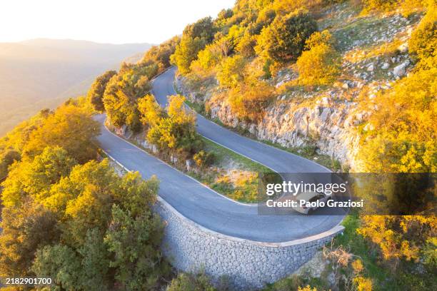 car traveling hairpin bend on mountain road - driving mountain road stock pictures, royalty-free photos & images